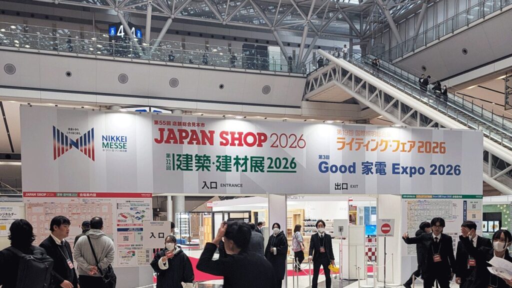 passiv energieが出展した展示会「日経メッセ 建築・建材展2026」の東京ビッグサイト会場入口に設置された大型案内看板の写真。看板には「JAPAN SHOP 2026」「建築・建材展2026」「ライティング・フェア 2026」「Good 家電 Expo 2026」のイベントロゴや入場口・退場口の案内が記載されており、多くの来場者が行き交う会場風景